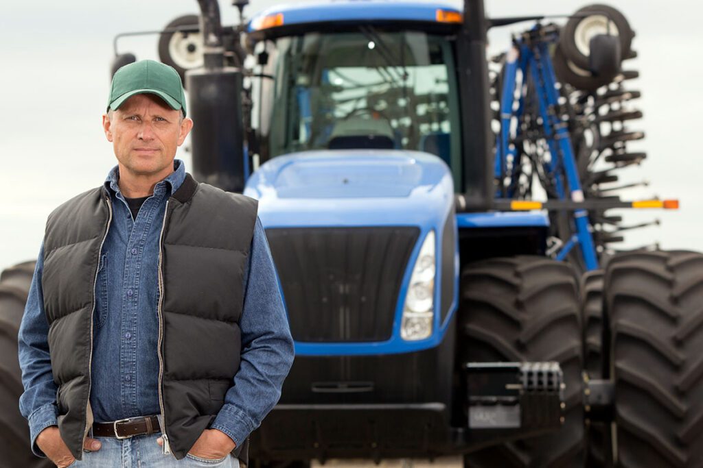 A farm worker in front of his tractor.